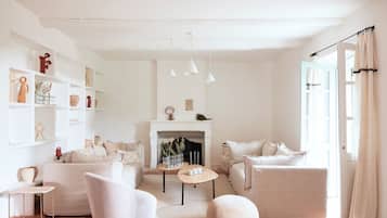 Un salon minimaliste avec une cheminée, des meubles blancs et une bibliothèque.