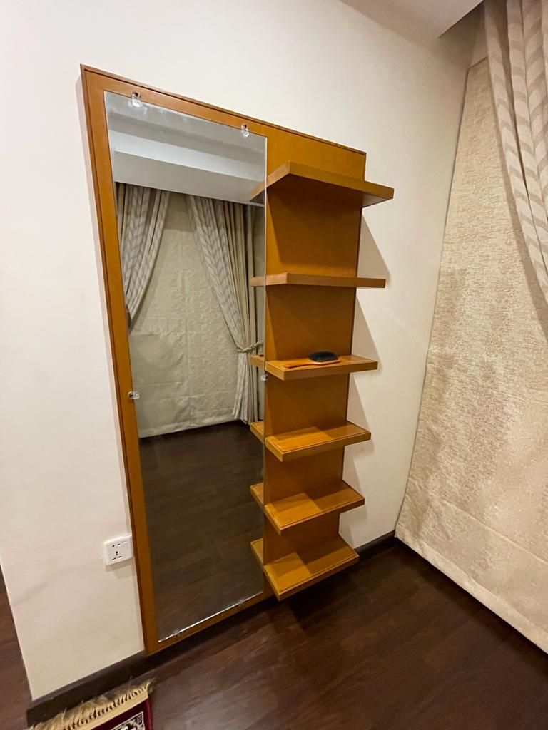 Una habitación con un armario de madera, un espejo y una cortina.