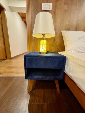 A room with a bed, a nightstand with a lamp, and a wooden floor. - GOHO ROOMS Murree (Murree)