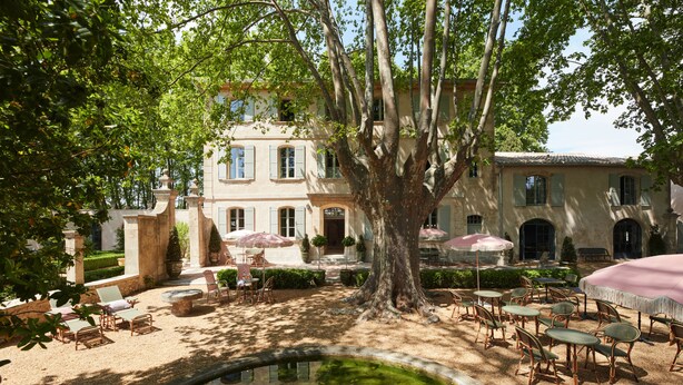 A courtyard with a large tree, outdoor seating, and a small pond.