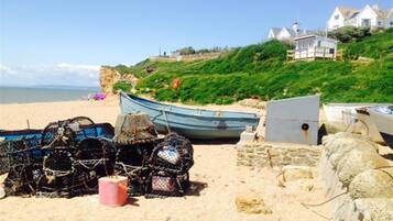 A beach with fishing gear, a boat, and a stone wall.