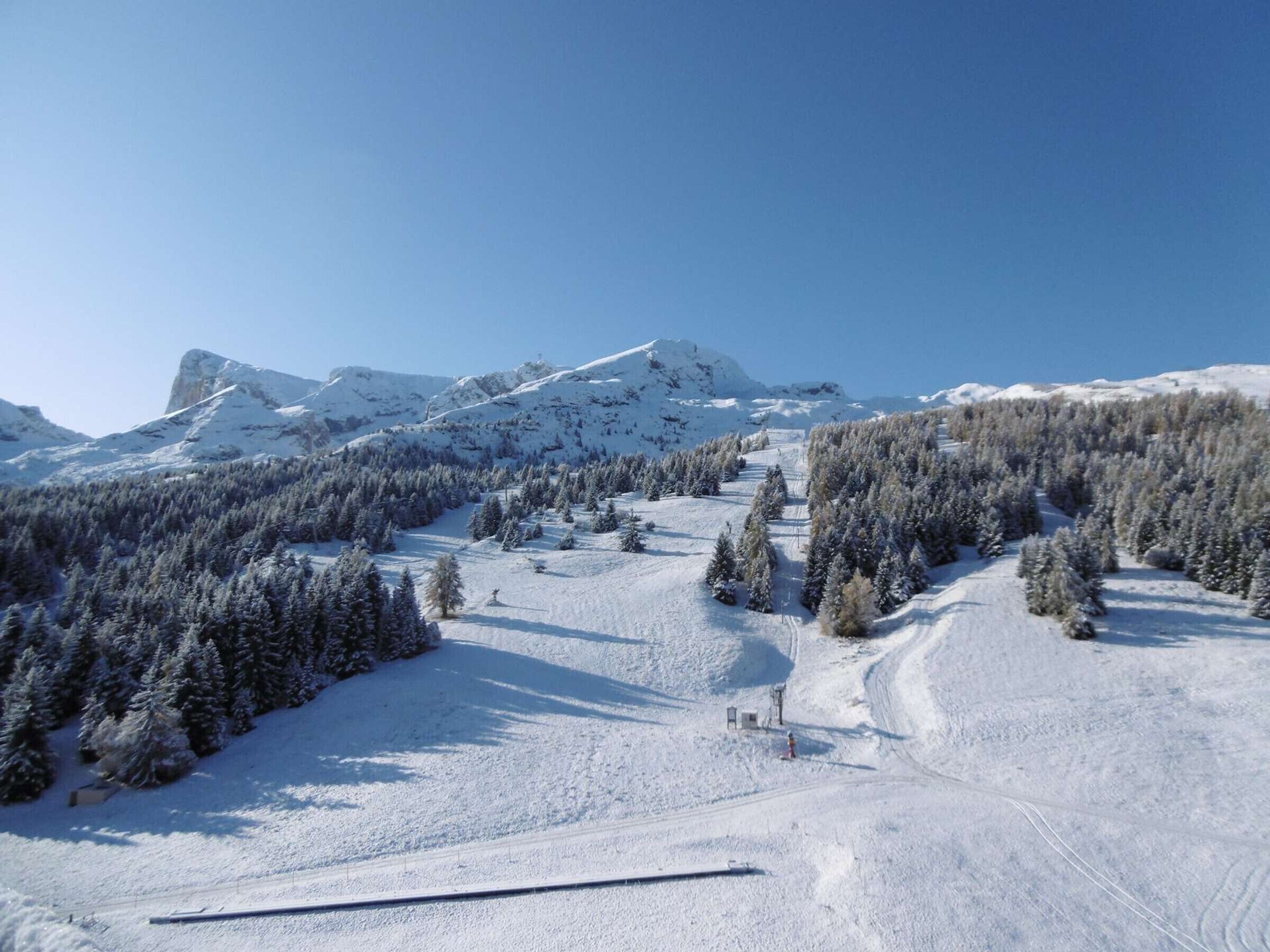Un paysage montagneux enneigé, avec des pistes de ski et un télésiège.