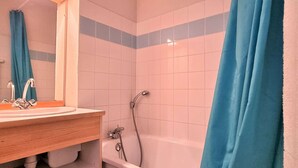 A bathroom with a white bathtub, a shower, and a sink with a mirror.