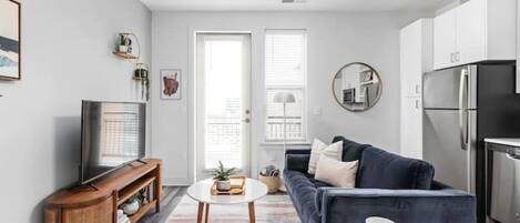 A modern living room with a dark blue sofa, a wooden TV stand, and a round coffee table.