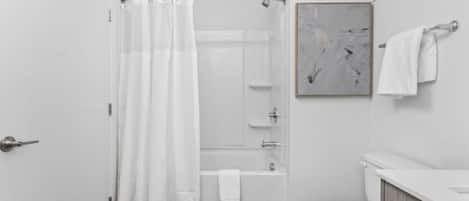 Een moderne badkamer met een douche, bad en toilet.