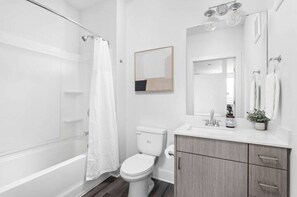 A modern bathroom with a bathtub, toilet, and vanity.