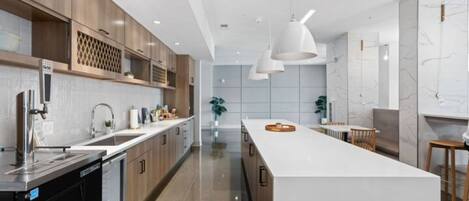 A modern kitchen with wooden cabinets, a large island, and pendant lighting.