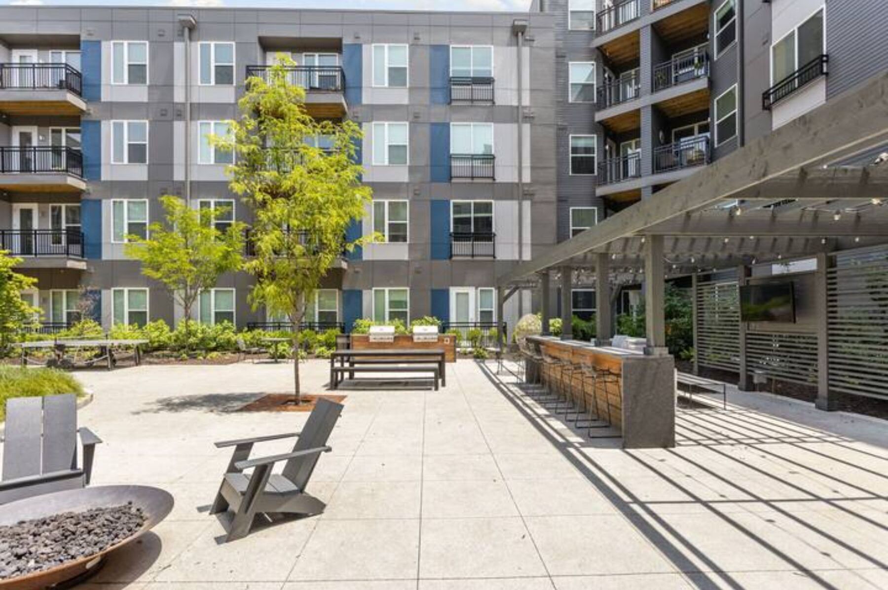 Un moderno edificio de apartamentos con varios balcones, zonas de estar al aire libre y un porche cubierto.