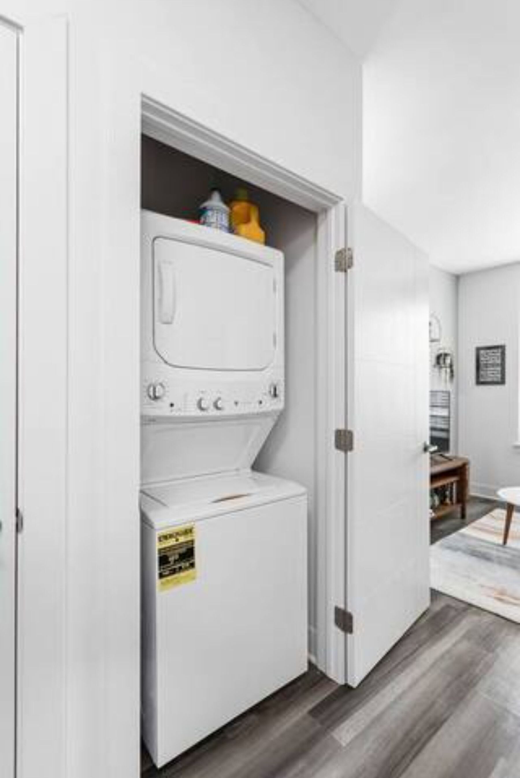 A laundry room with a washer and dryer, a caution sign on the dryer, and a door leading to another room.