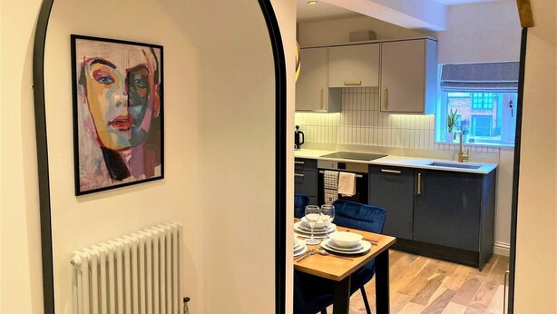 A modern kitchen with a dining area, a radiator, and a painting on the wall.