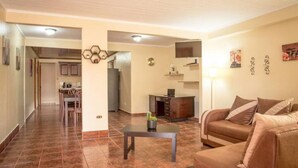 A spacious living area with a brown leather sofa, a small coffee table, and a kitchen in the background.