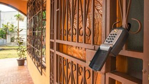 A metal gate with a keypad lock, a brick pathway, and a potted plant.
