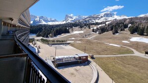 A view from a balcony overlooking a mountainous landscape with snow-capped peaks, a ski resort, and a clear blue sky. - Cozy studio for 4 with terrace, near slopes and shops (Le Dévoluy)