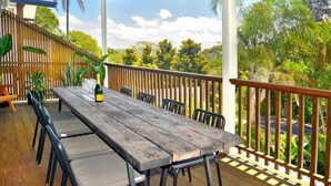 A wooden deck with a table and chairs, surrounded by a wooden fence and lush greenery. - Massinger Views Byron Bay (Byron Bay)