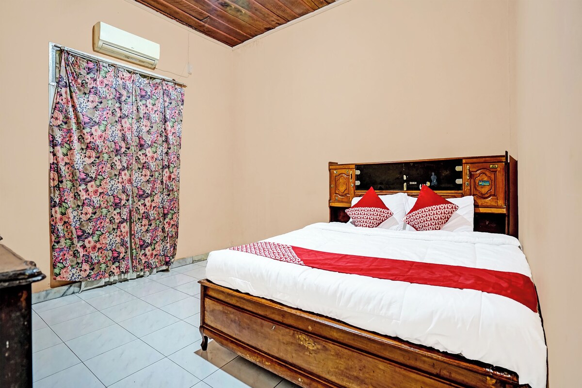 Une chambre à coucher avec un lit en bois, des rideaux à motifs floraux et un sol carrelé.