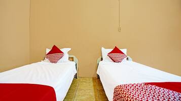 A room with two beds, each with white bedding and red pillows.