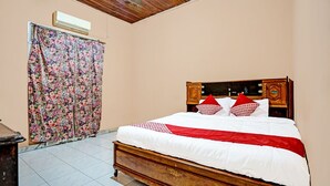 Een slaapkamer met een houten bed, bloemen gordijnen en een betegelde vloer.