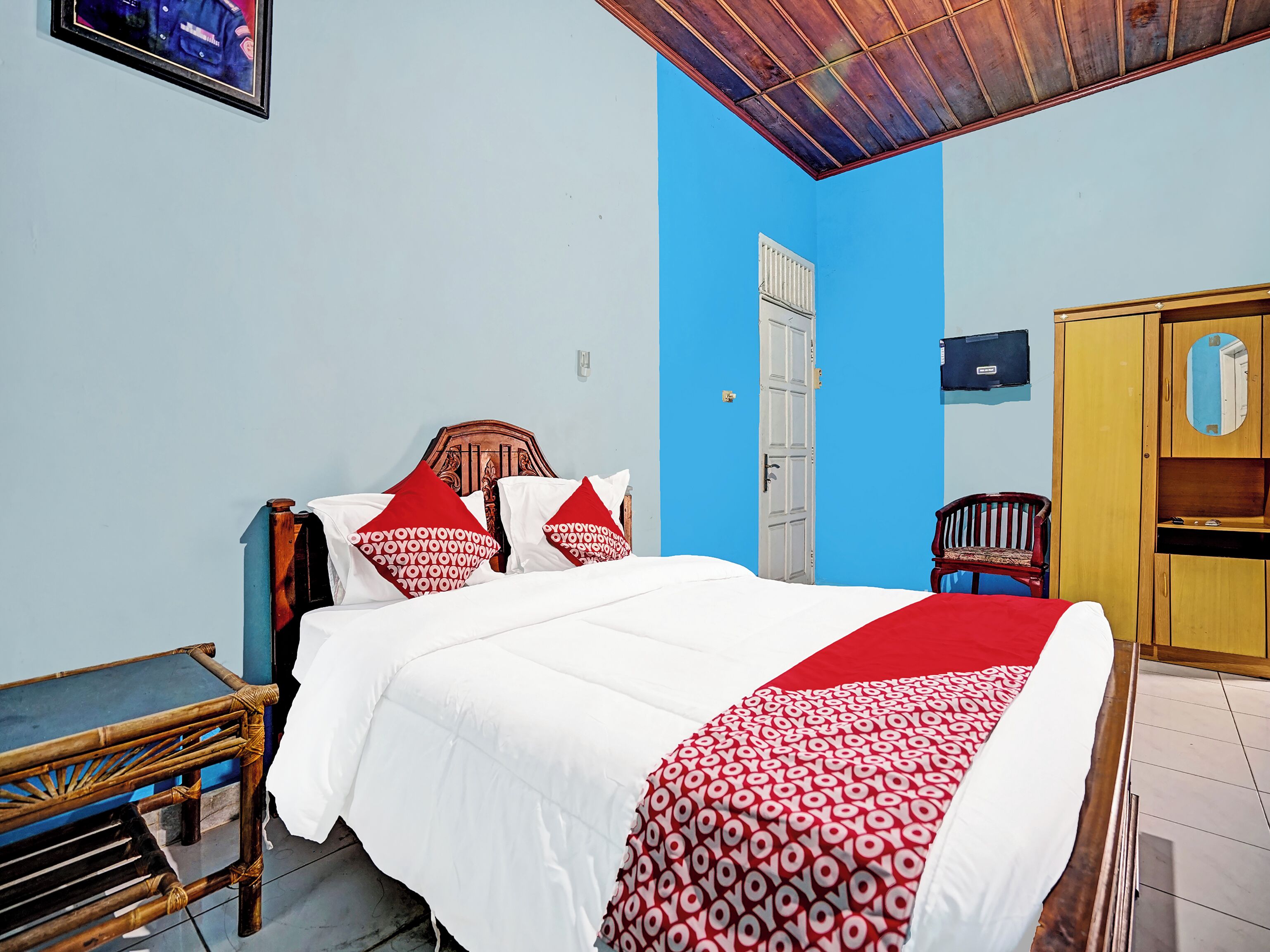 Un dormitorio con cama, armario de madera, banco y puerta.