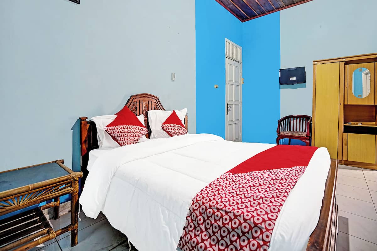 Un dormitorio con cama, armario de madera, banco y puerta.
