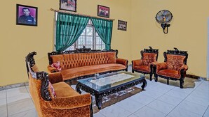 Een woonkamer met een bank, twee fauteuils, een bijzettafeltje en een ventilator.