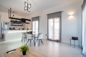 A modern kitchen with a central island, white dining chairs, and a small table with a plant.