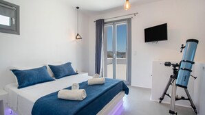 Une chambre à coucher avec un lit, un télescope, une télévision et une porte-fenêtre coulissante.
