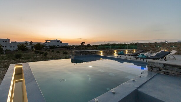 Une piscine avec des chaises longues et une vue sur le coucher de soleil.