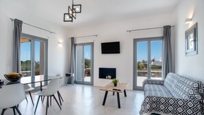Un salon moderne comprenant un canapé, une table à manger, des chaises, un téléviseur et une cheminée.
