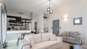 Uma sala de estar moderna com sofá, uma mesa de centro e uma área de jantar, com uma cozinha ao fundo.