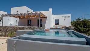 Um edifício moderno com piscina, espreguiçadeiras e uma parede de pedra.