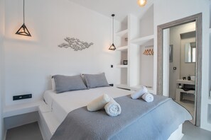 A modern bedroom with a bed, two pillows, a towel, a wall art piece, and a hanging light fixture. - Villa 'Blue Bell Resort Sunrise' with Sea View, Wi-Fi and Air Conditioning (Paros)