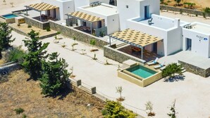 Um resort moderno com vários edifícios brancos, piscinas ao ar livre e vista para o mar.