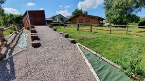 A gravel path leading to a wooden building with a green tarp-covered area.