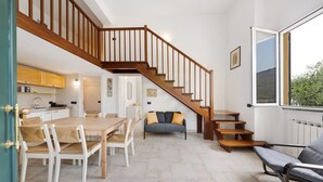 Un vaste espace de vie comprenant un escalier en bois, une table à manger avec des chaises et un canapé.