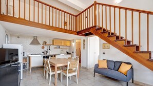 Une cuisine moderne avec un coin repas, un escalier et un salon doté d’un canapé.