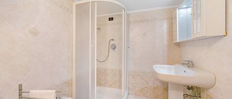 Un baño con ducha, lavabo y toallero.