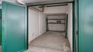 An interior space with a concrete floor, green doors, and a white wall with a visible pipe. - Apartment 'Mari Fior' with Sea View, Balcony and Wi-Fi (San Bartolomeo)