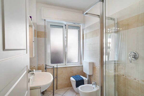 Ein Badezimmer mit Duschkabine aus Glas, Toilette, Waschbecken und Bidet.