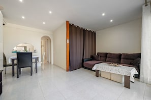 Un soggiorno moderno con un tavolo da pranzo, un divano e un piccolo tavolino con un oggetto decorativo.
