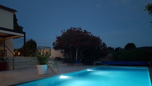 Une piscine à l’eau d’un bleu cristallin, entourée d’une terrasse avec des marches menant à un bâtiment.