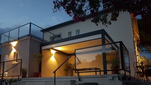 Une maison moderne dotée d’une extension en verre, d’un espace salon extérieur et d’un escalier.