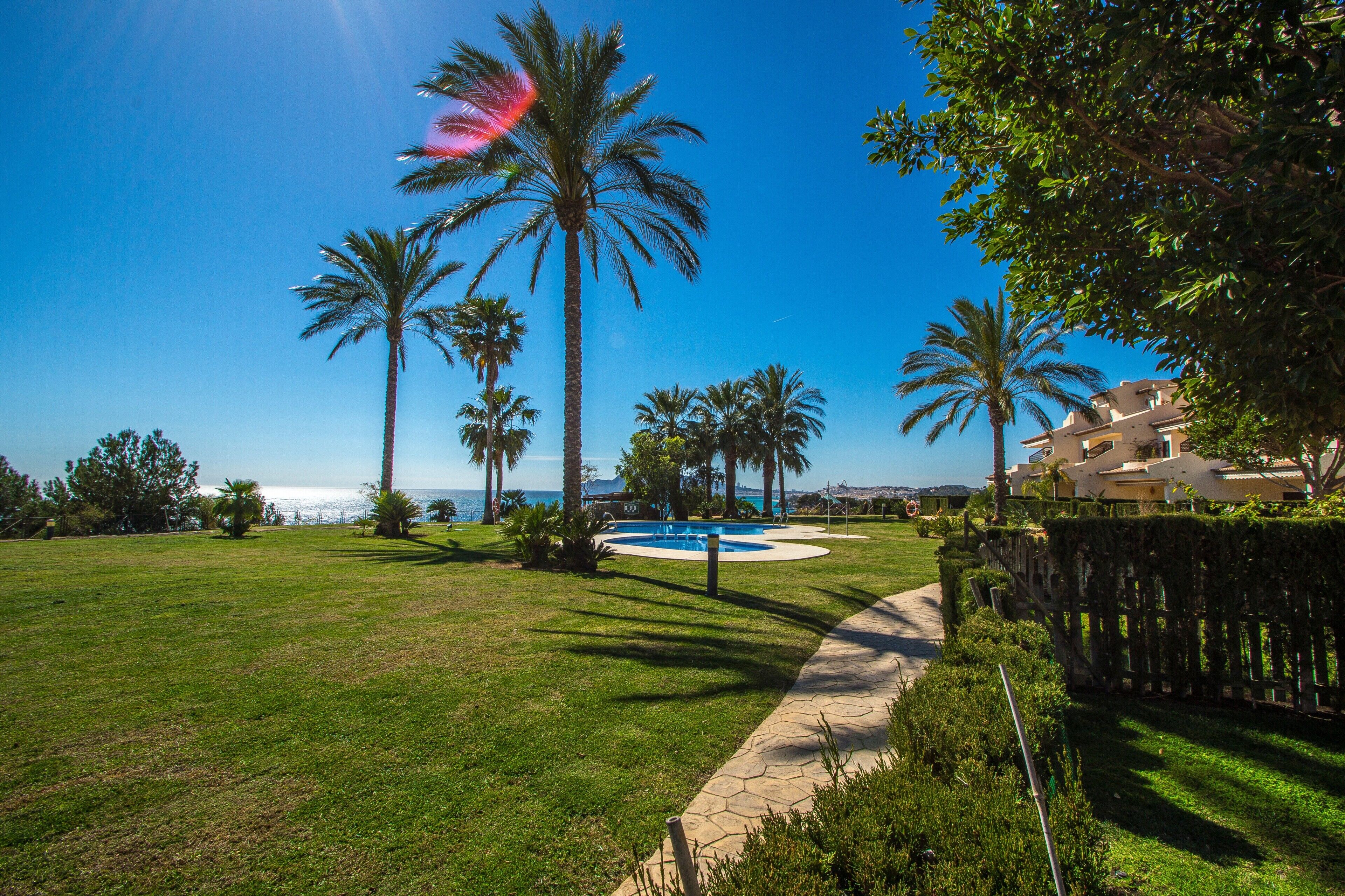 A well-maintained lawn, a swimming pool, and a view of the ocean.