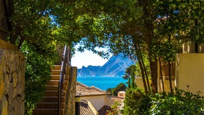 A stone staircase leading to a building with a view of the sea and mountains.