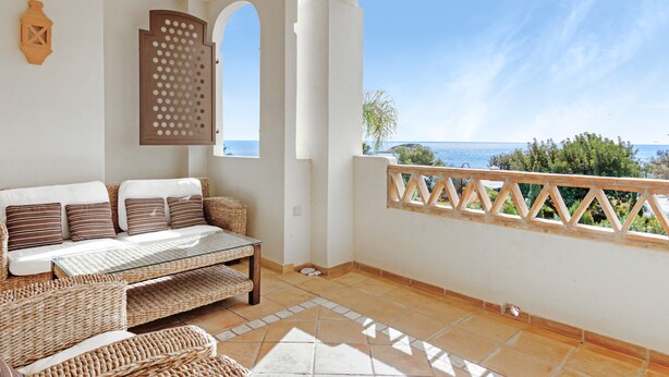 A balcony with a view of the sea, a wicker sofa, a glass table, and a decorative screen. - Apartment 'Villa Gadea 4-3' with Sea View, Wi-Fi and Air Conditioning (ALTEA)