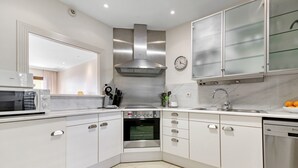 A modern kitchen with white cabinets, stainless steel appliances, a clock, and a dishwasher. - Apartment 'Villa Gadea 4-3' with Sea View, Wi-Fi and Air Conditioning (ALTEA)