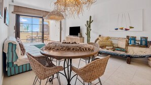A cozy living area with a round table, wicker chairs, a sofa, a TV, and a cactus. - Villa Gadea 7-2 Apartment with Sea Views, Wi-Fi, and Air Conditioning (Altea)