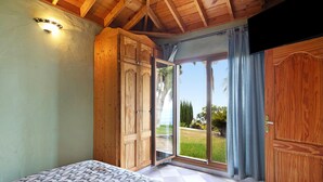 Une chambre à coucher comprenant un lit, une armoire en bois et une porte-fenêtre coulissante donnant sur un balcon.