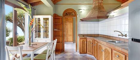 A kitchen with a wooden ceiling, a tiled floor, and a view of the outdoors.