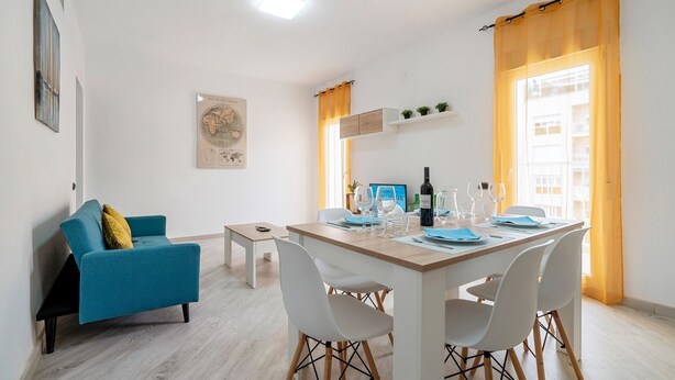 A modern living room with a sofa, dining table, chairs, a small coffee table, and a bench.