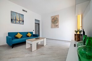 A modern living room with a blue sofa, a white coffee table, and a world map on the wall.